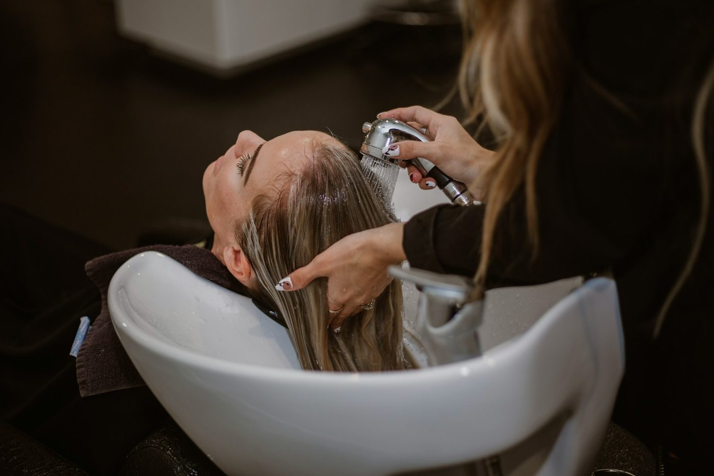 A hairdresser washing a client's hair at a basin